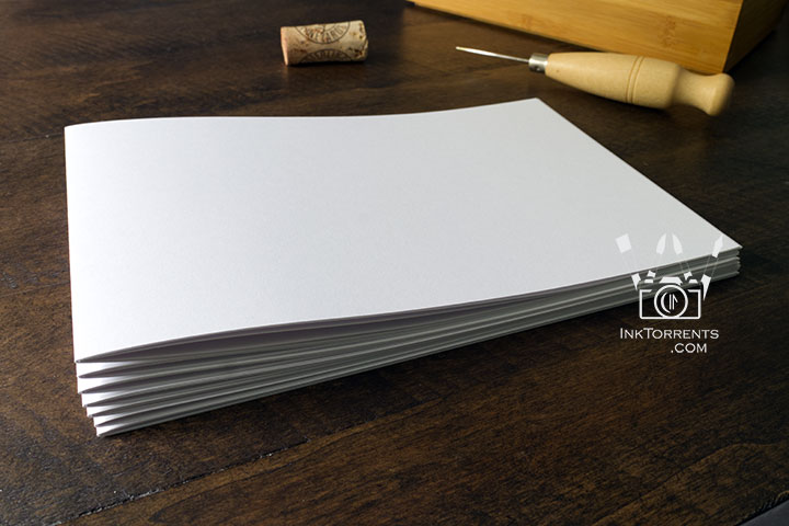 Stack of folded paper signatures in the bookbinding process — InkTorrents Graphics