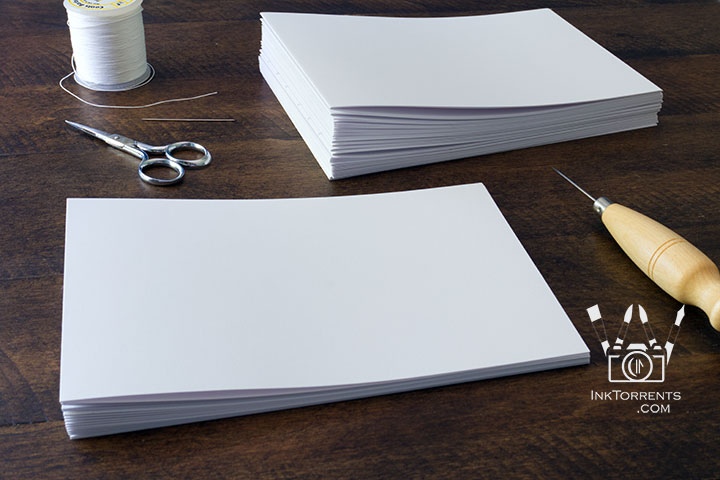 Stack of folded paper signatures in the bookbinding process by InkTorrents Graphics